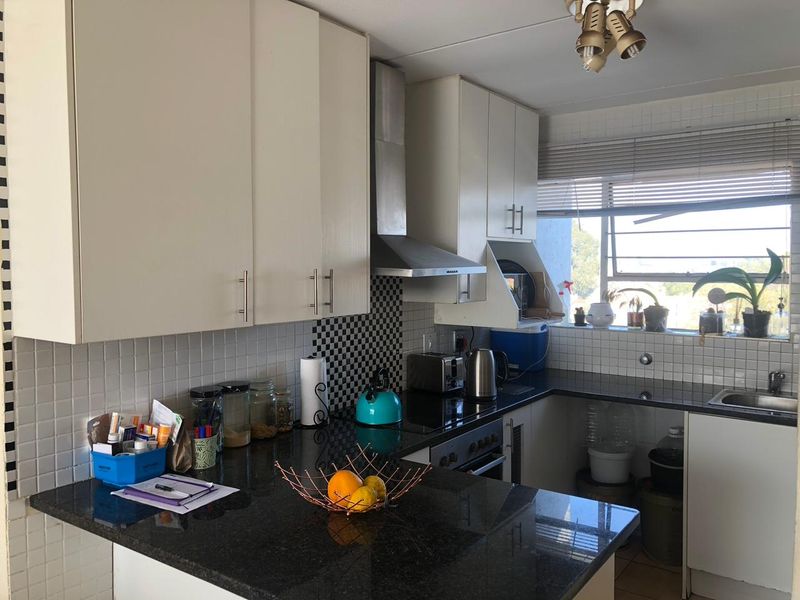 Functional kitchen featuring granite countertops, stainless steel oven and extractor fan, and ample upper cabinetry with a tiled backsplash.
