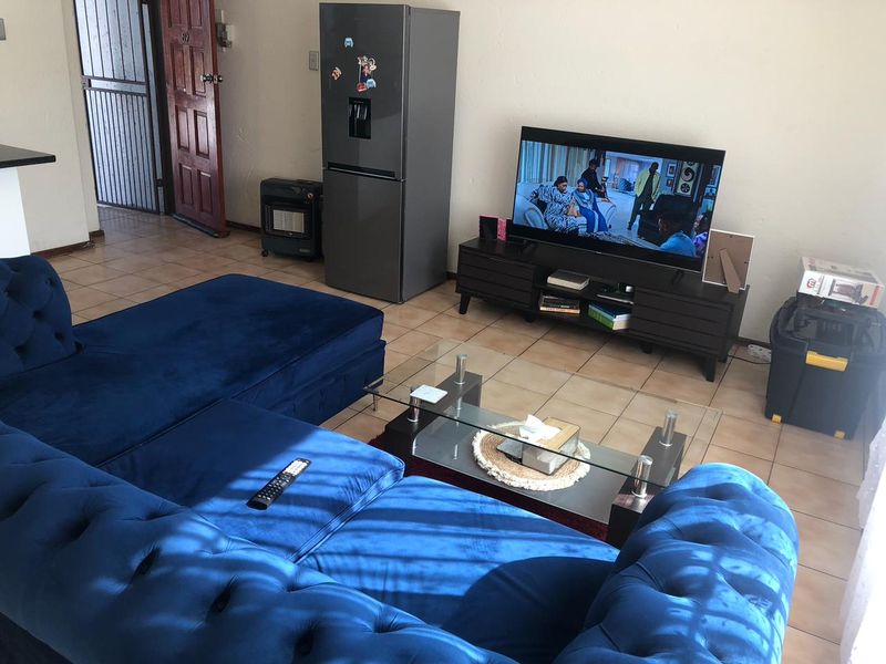 A living room area featuring tiled flooring and direct access to the entrance with a security gate.