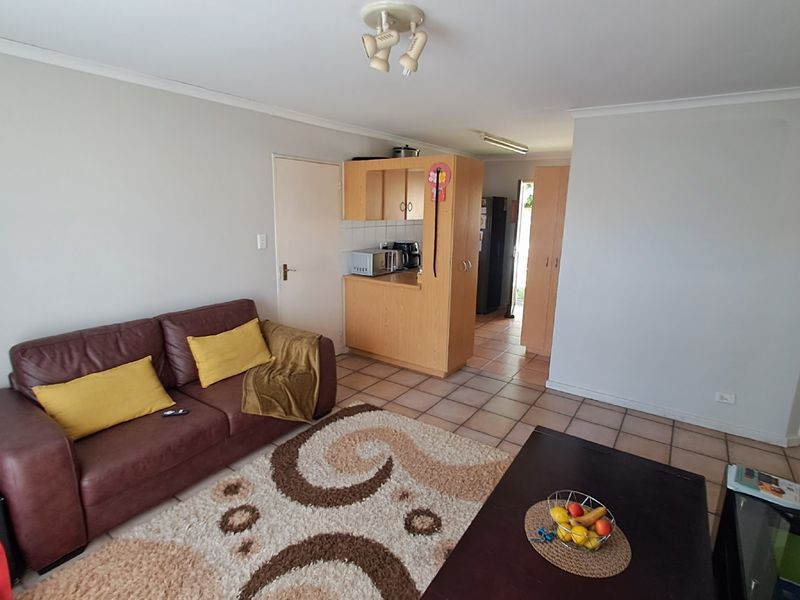 Open plan living area featuring tiled flooring and a compact kitchen space with built-in cabinetry.