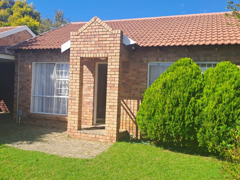 A charming face-brick townhouse exterior featuring a covered entrance porch, tiled roof, and a well-maintained front garden with paved walkway.