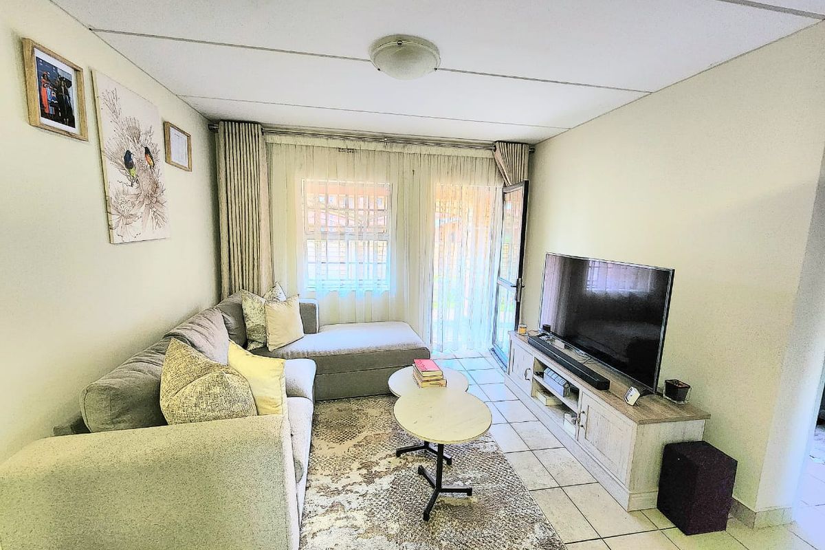 A functional living room featuring tiled flooring and a sliding glass door providing access to the exterior.