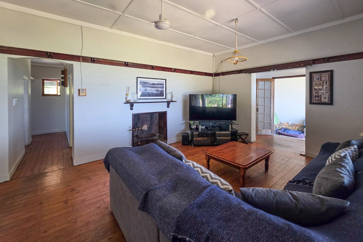 Spacious living room featuring original hardwood flooring, a traditional fireplace, and classic timber picture rails, offering a warm and character-filled atmosphere.