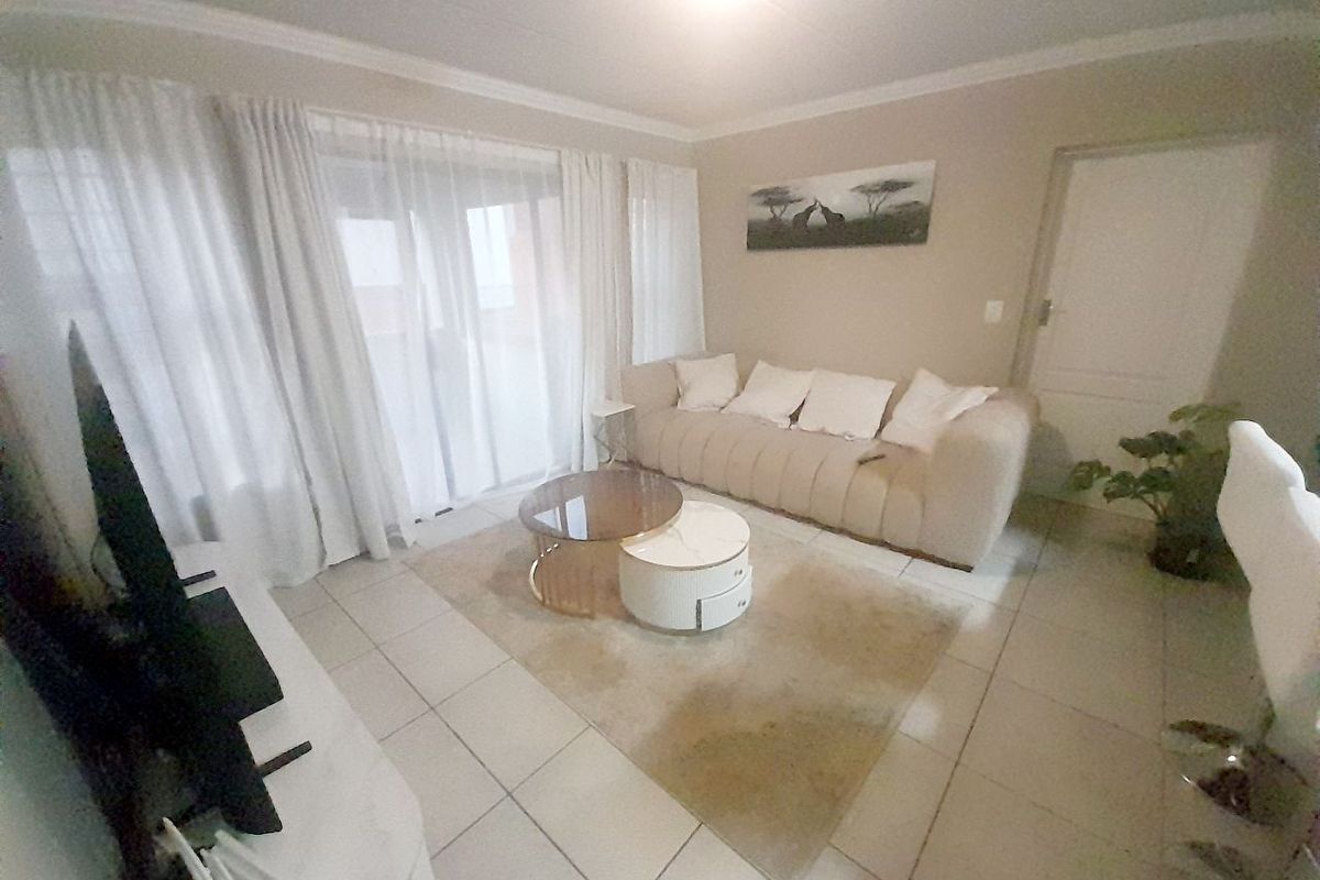 A bright living room featuring tiled flooring, neutral wall tones, and large sliding glass doors that provide access to an outdoor area.