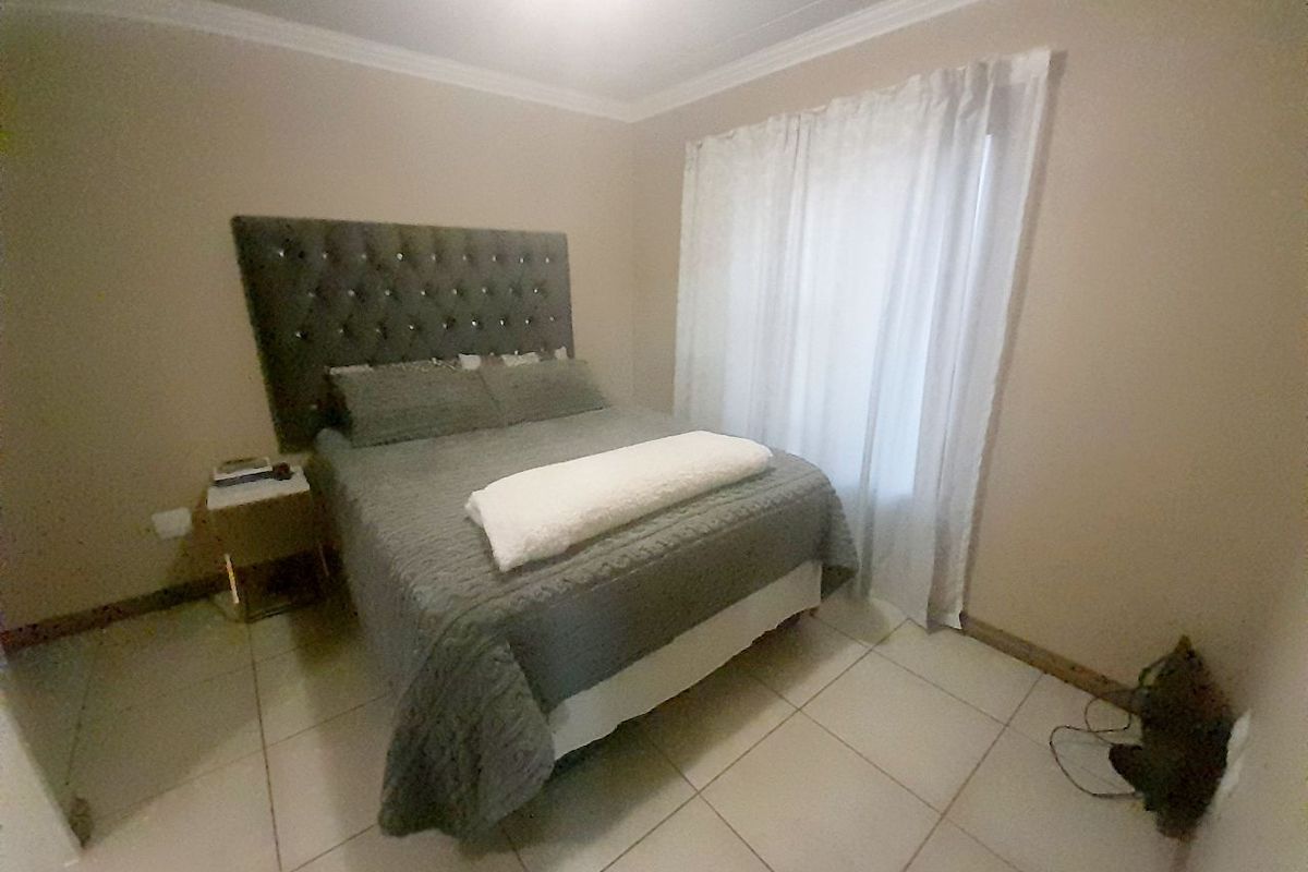 A bedroom featuring neutral wall tones, tiled flooring, and crown molding, providing a clean and functional living space.