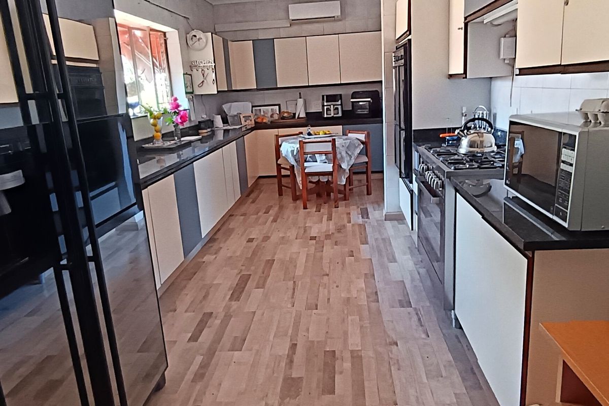 A functional kitchen featuring built-in cabinetry, granite countertops, a gas cooktop, and integrated oven, with durable laminate flooring throughout.
