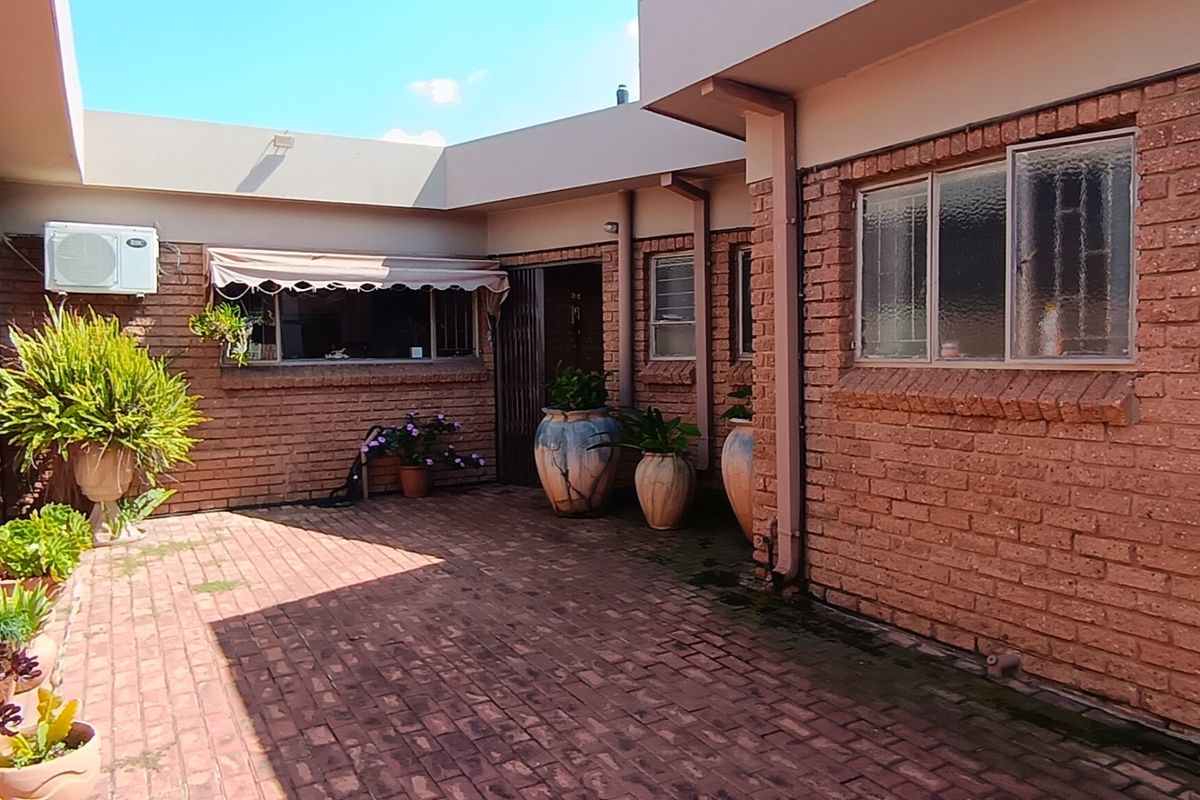 A private rear courtyard featuring face brick walls, brick paving, and a retractable awning, providing a functional outdoor space.