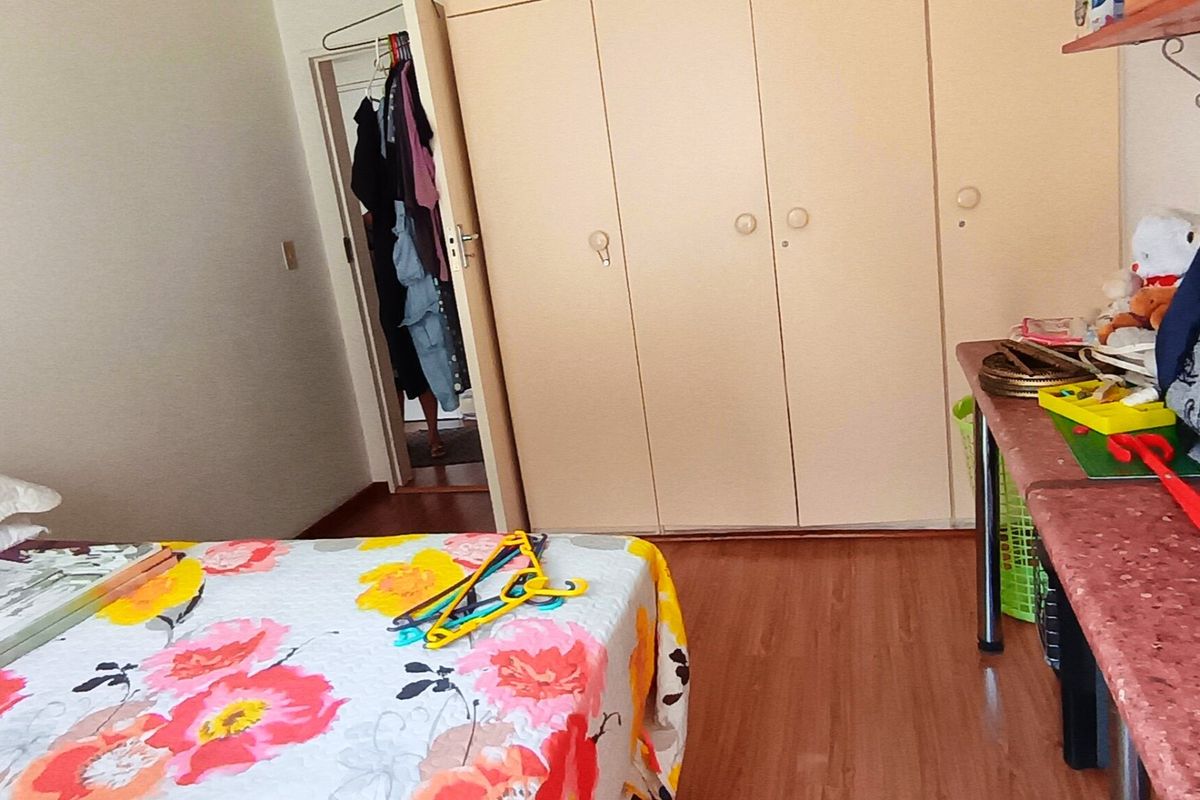 A bedroom featuring laminate flooring and a large built-in wardrobe with multiple doors.
