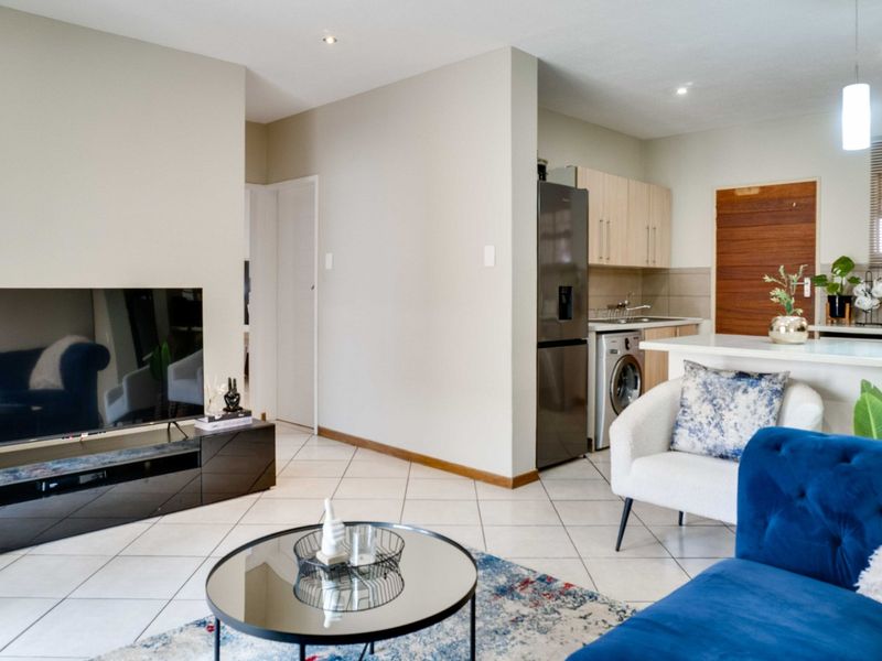 Open-plan living area featuring tiled flooring, recessed lighting, and a functional kitchen with built-in cabinetry and a breakfast counter.