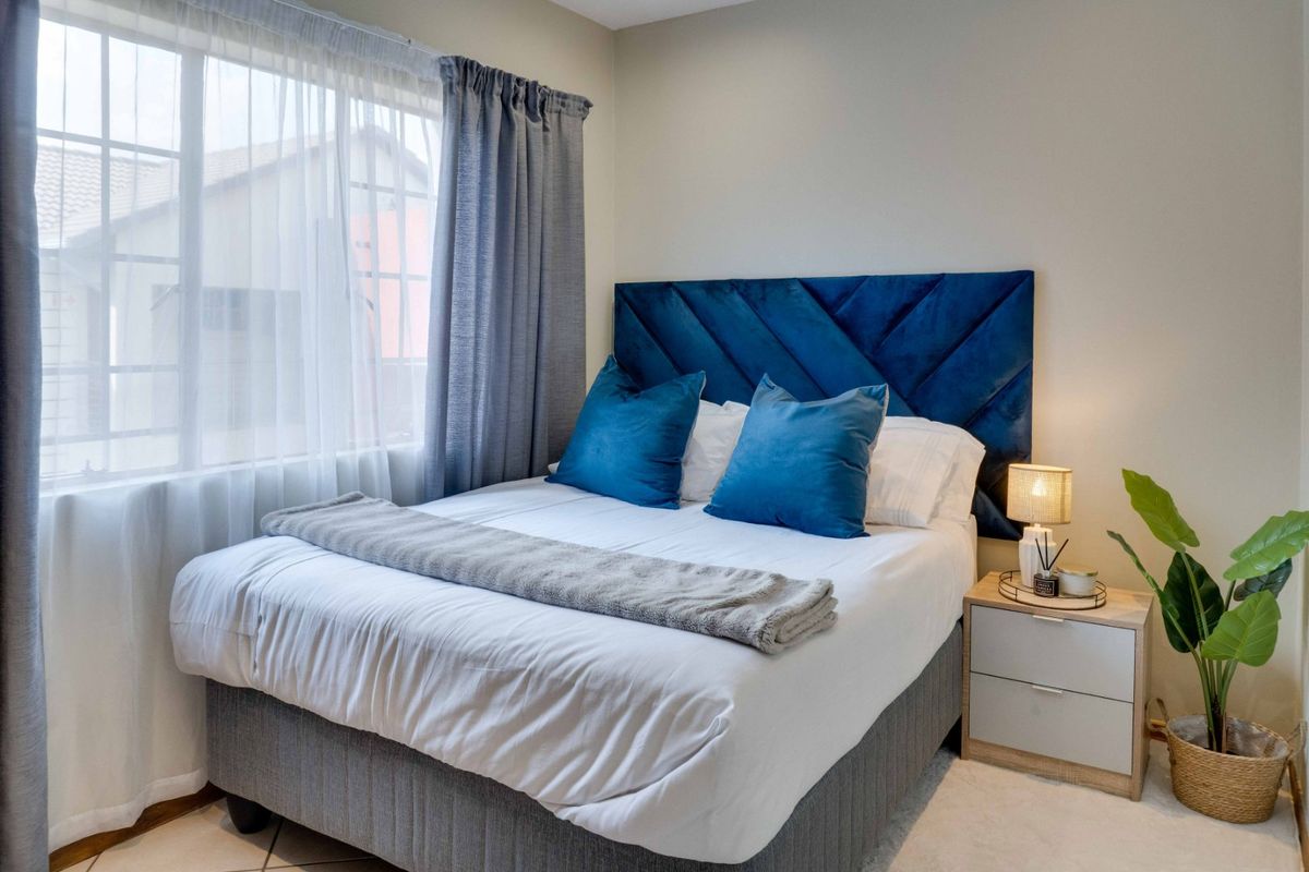 A well-maintained bedroom featuring neutral wall finishes and natural light through a large window.