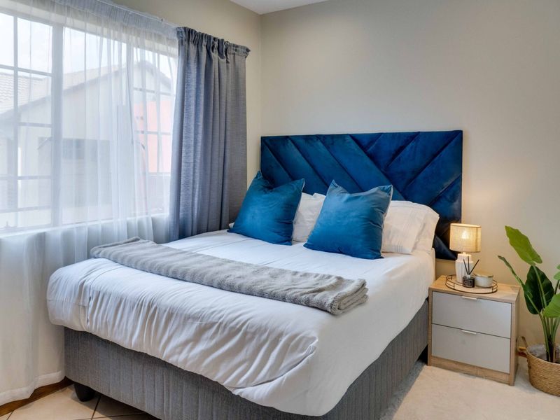 A well-maintained bedroom featuring neutral wall finishes and natural light through a large window.