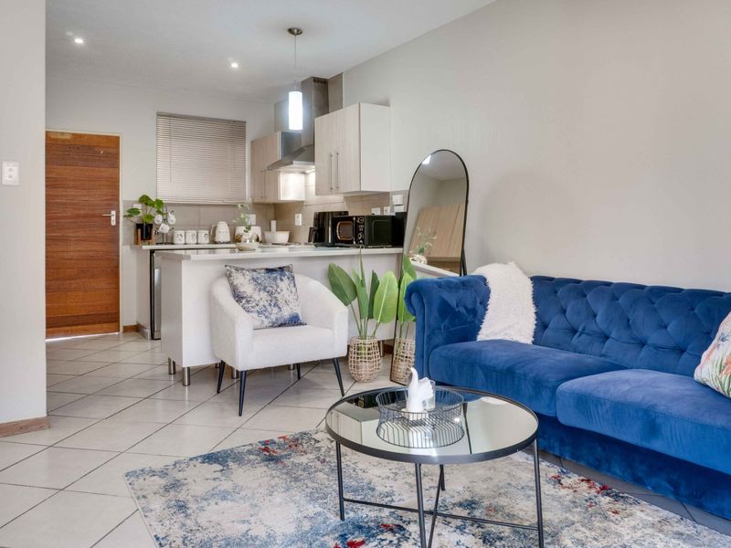 An open-plan living area featuring a modern kitchen with stone countertops, tiled flooring, and recessed lighting, seamlessly connected to the lounge space.