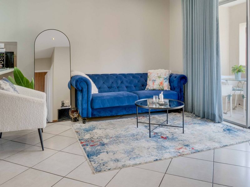 A bright living room featuring tiled flooring and a large sliding glass door providing access to an outdoor balcony area.