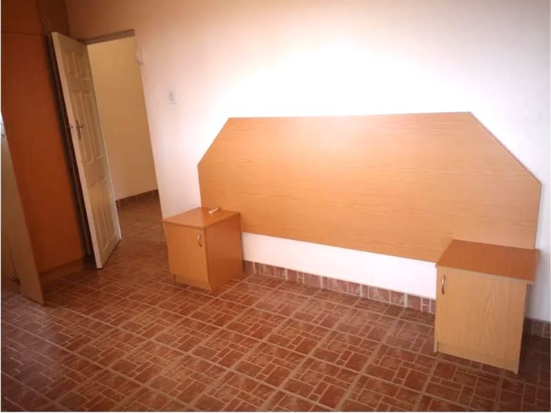 A bedroom featuring built-in cabinetry including a headboard, bedside tables, and a wardrobe, finished with tiled flooring.