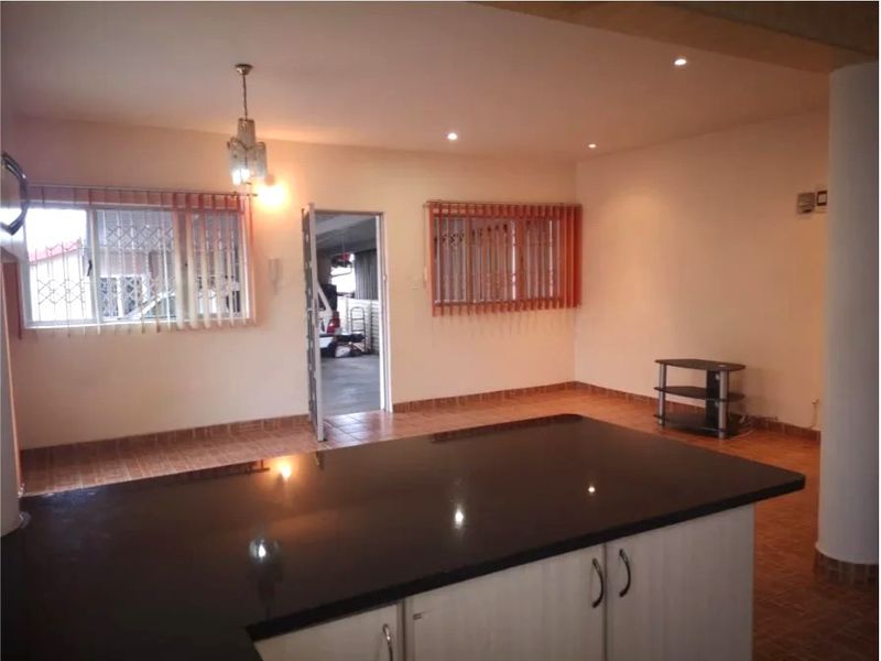 Open plan living area featuring a kitchen island with granite countertops, tiled flooring, and recessed lighting, offering a functional and versatile space.