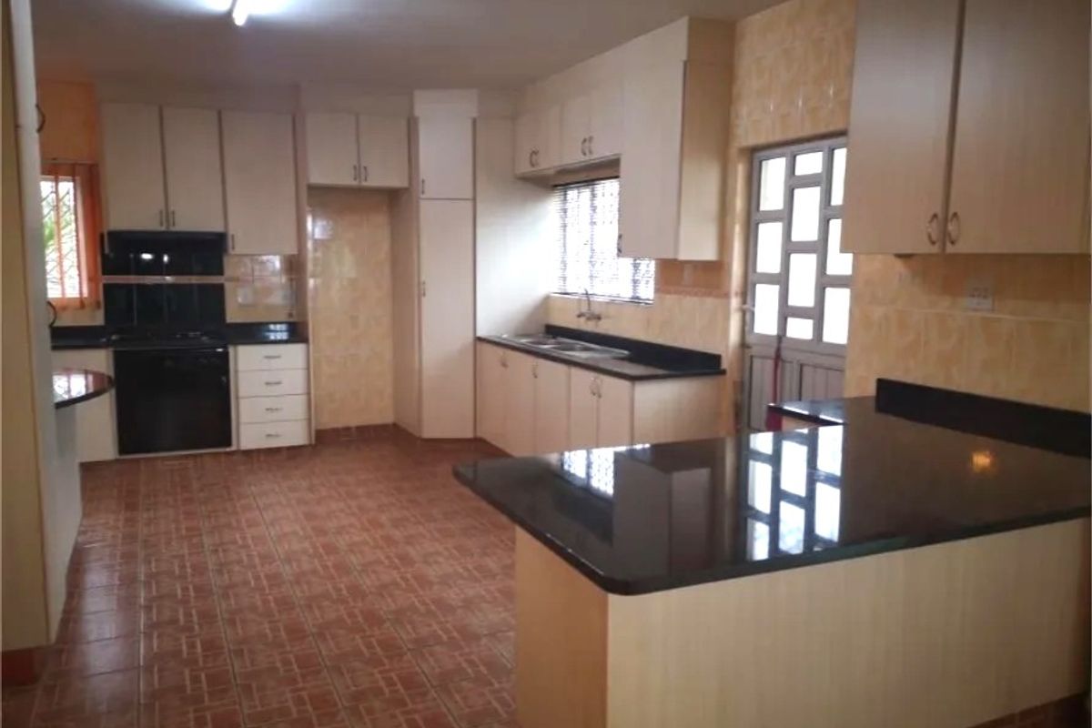 Spacious kitchen featuring built-in cabinetry, granite countertops, a double sink, and integrated cooking appliances with tiled flooring and backsplash.