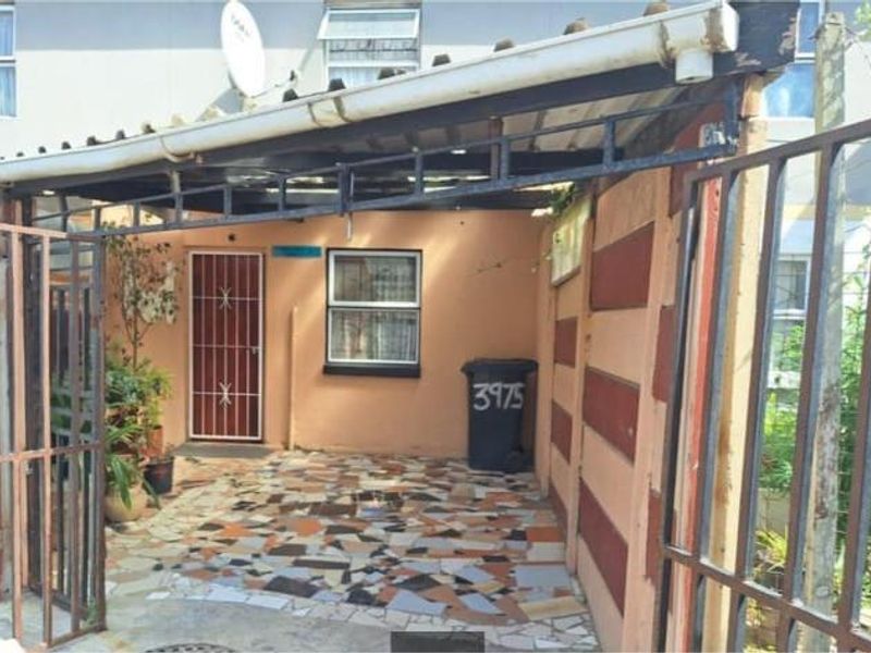 Front entrance area featuring a paved courtyard, metal security gate, and covered entryway with a satellite dish.