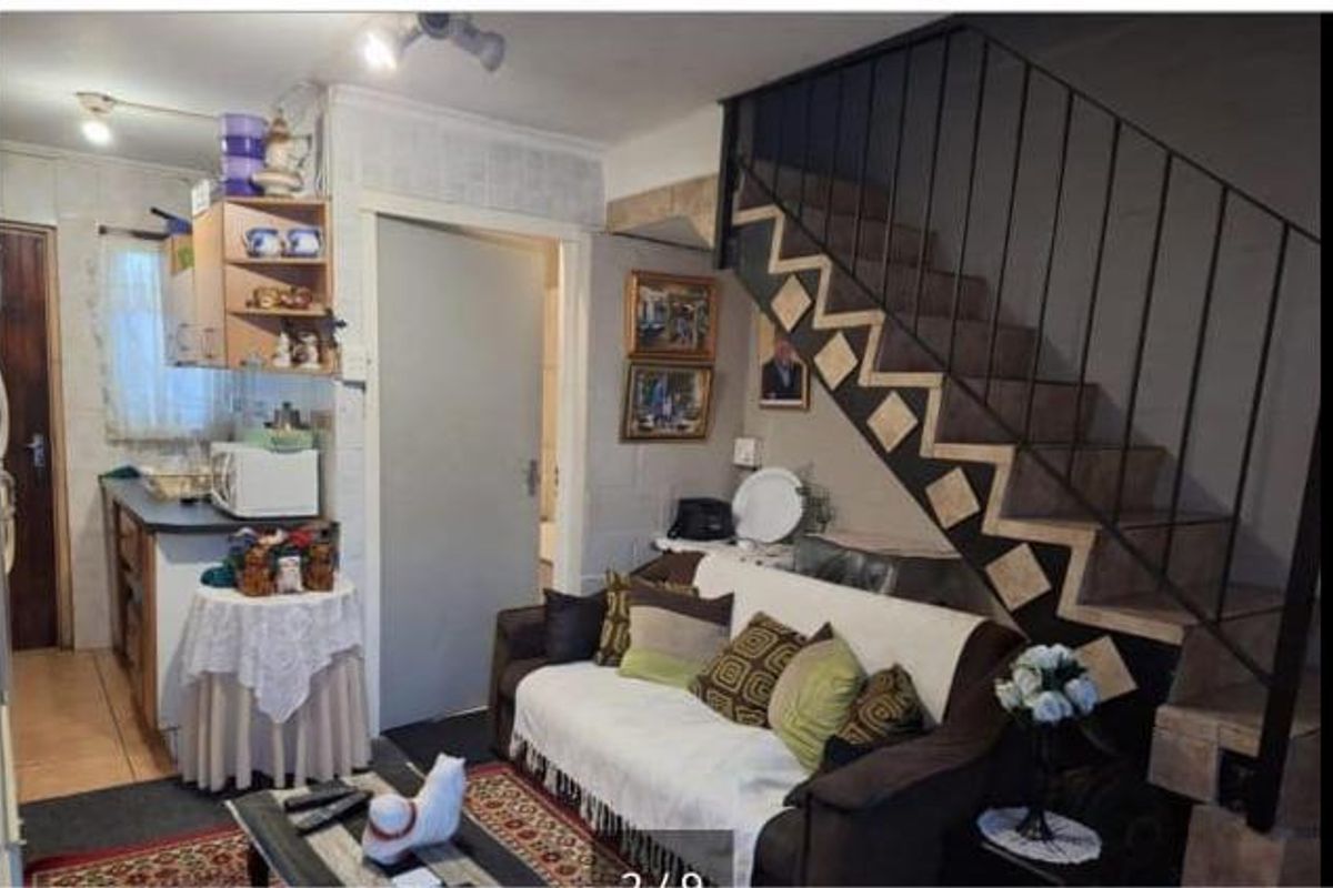 An open-plan living area featuring a staircase with decorative tiling and an adjacent kitchen space with built-in cabinetry.