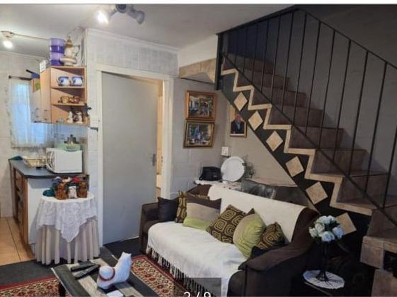 An open-plan living area featuring a staircase with decorative tiling and an adjacent kitchen space with built-in cabinetry.