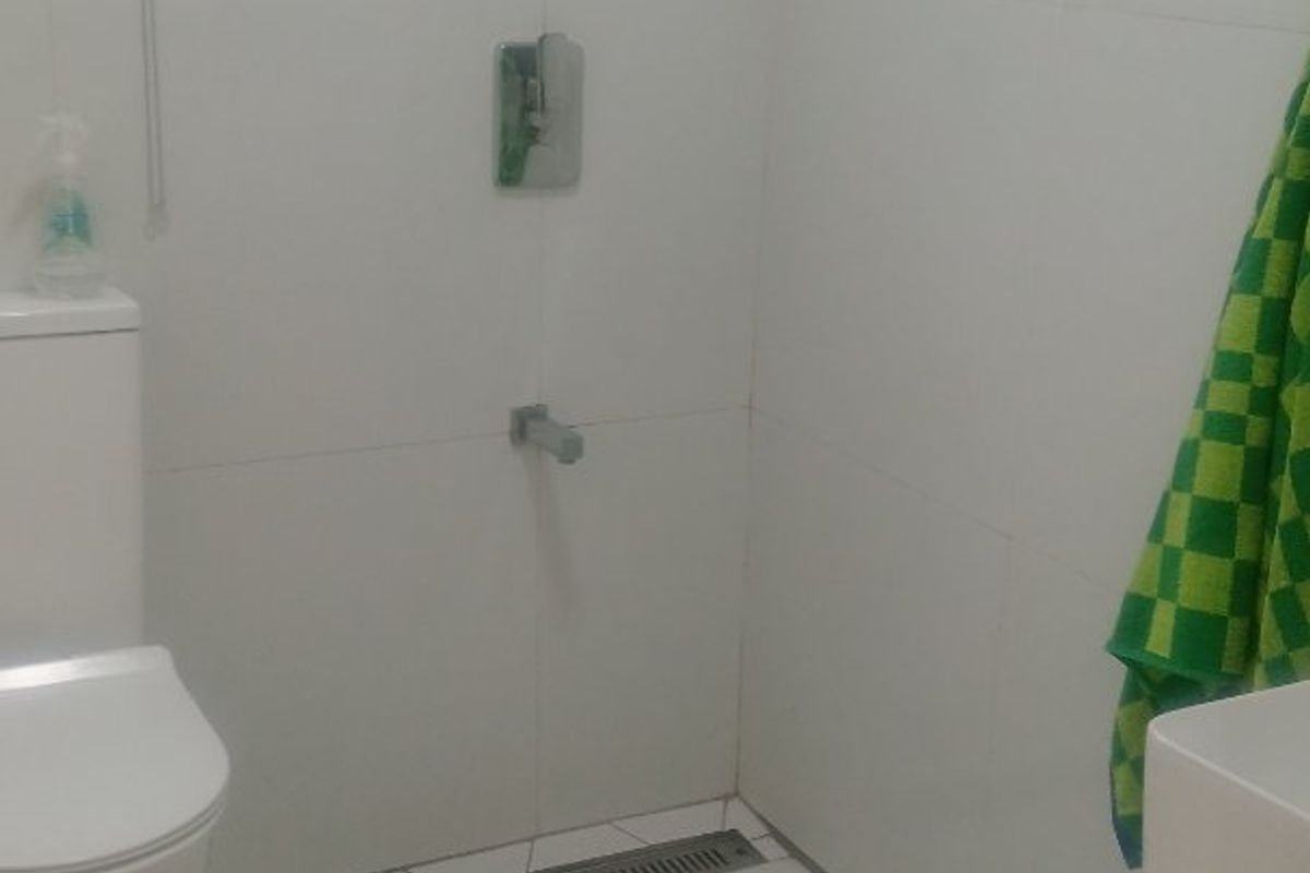 A modern bathroom featuring white hexagonal floor tiles, a wall-mounted toilet, a wall-mounted basin, and a sleek linear shower drain.