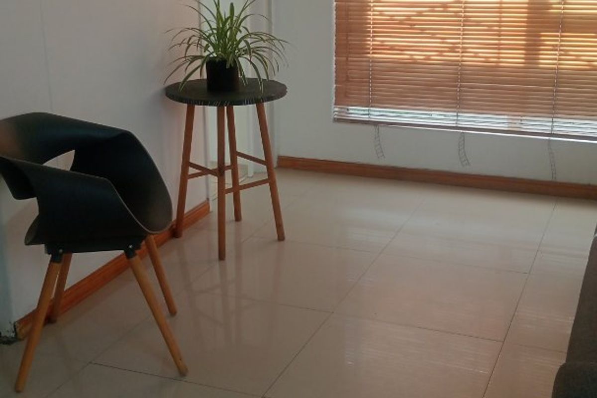 A bright living area featuring neutral tiled flooring and fitted venetian blinds, offering a clean and functional space ready for personalization.