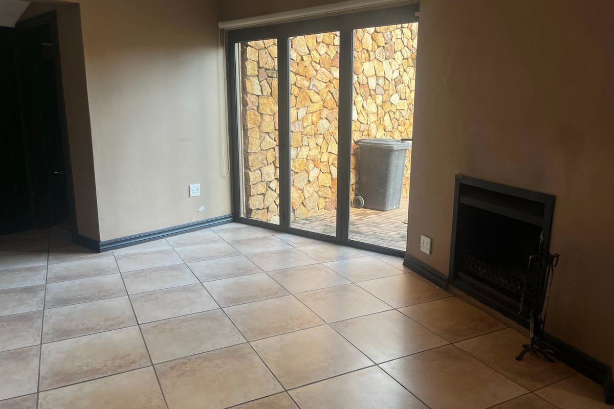 An empty living room featuring tiled flooring, a built-in fireplace, and large sliding glass doors providing access to an outdoor area.