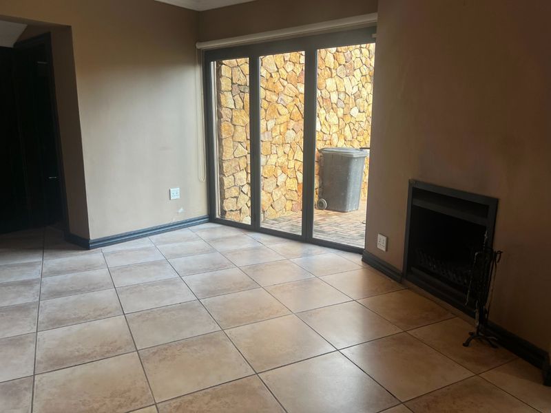 An empty living room featuring tiled flooring, a built-in fireplace, and large sliding glass doors providing access to an outdoor area.