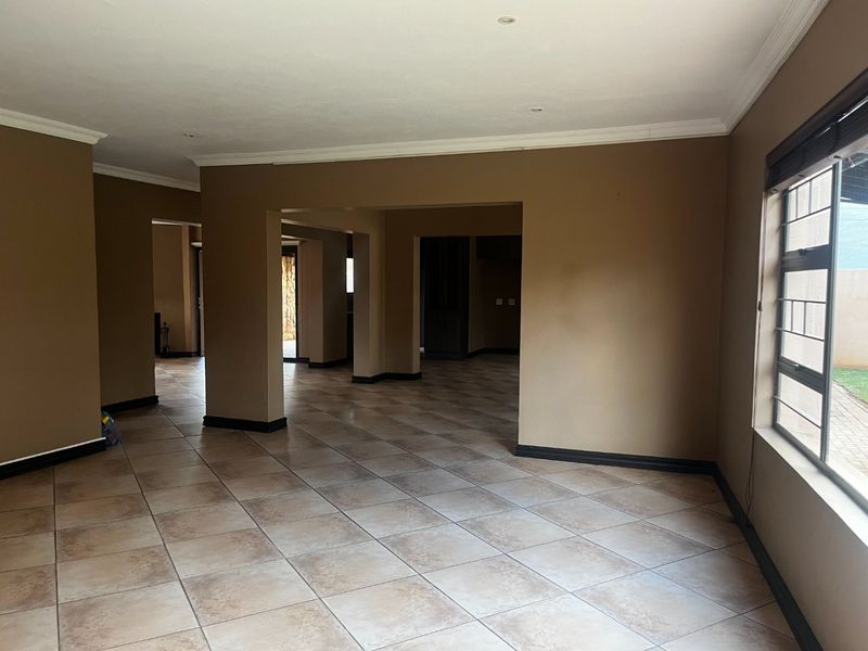 Spacious open-plan living area featuring neutral wall tones, ceramic tiled flooring, and recessed lighting, offering a versatile layout for various living arrangements.
