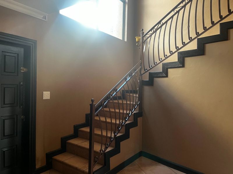 Entrance foyer featuring a tiled staircase with a decorative wrought iron balustrade and a solid entrance door.