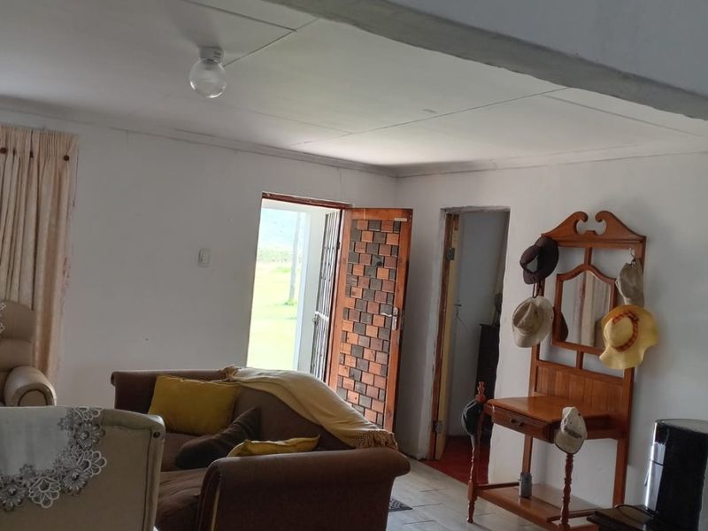 A living area featuring tiled flooring, an exposed ceiling beam, and direct access to the exterior through a timber door.