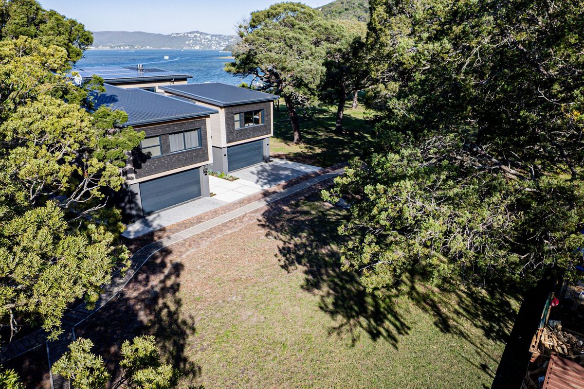 Aerial view of a modern residential property featuring dual garages, landscaped grounds, and scenic water views.