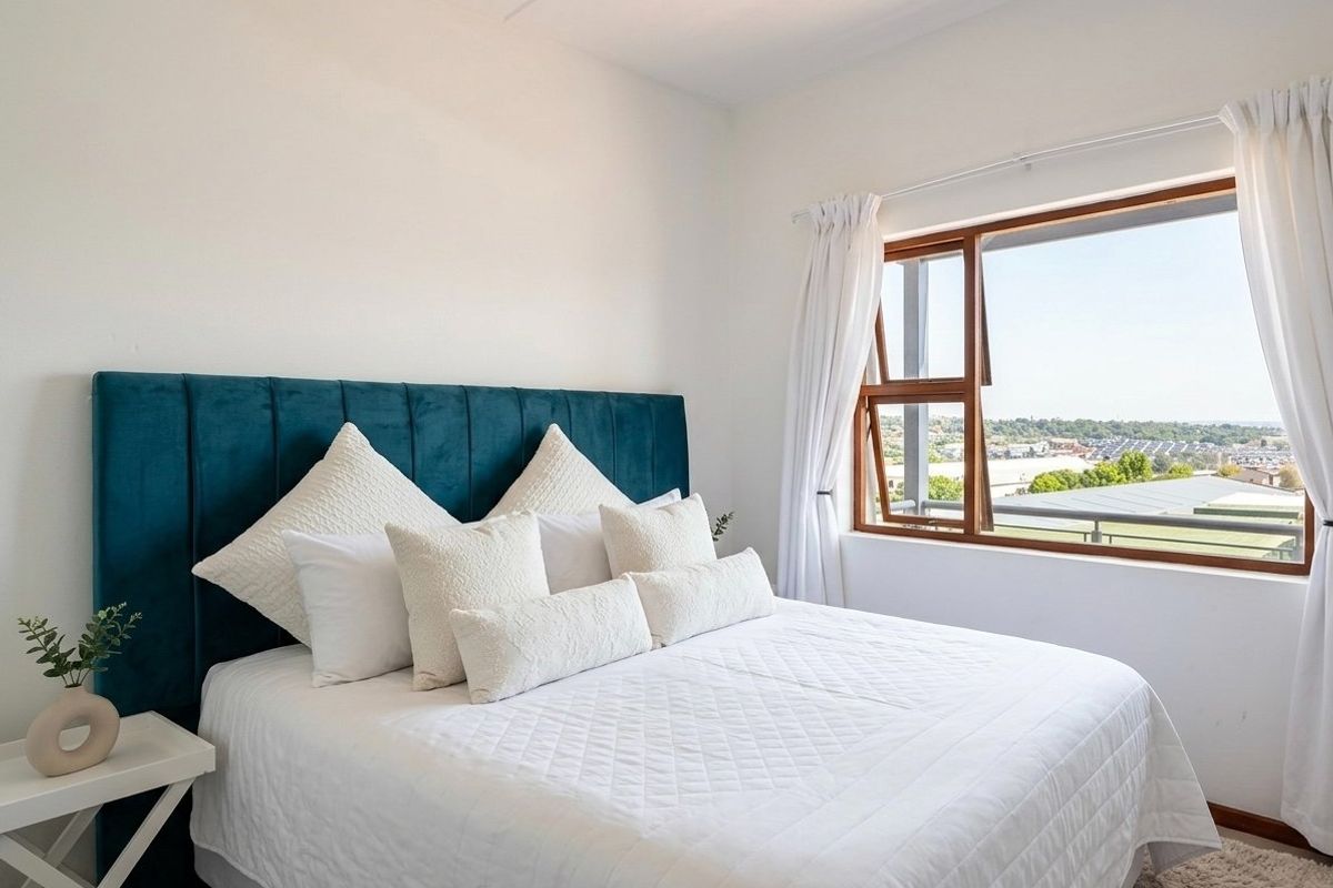 A bright and well-maintained bedroom featuring a timber-framed window with natural light and neutral finishes.
