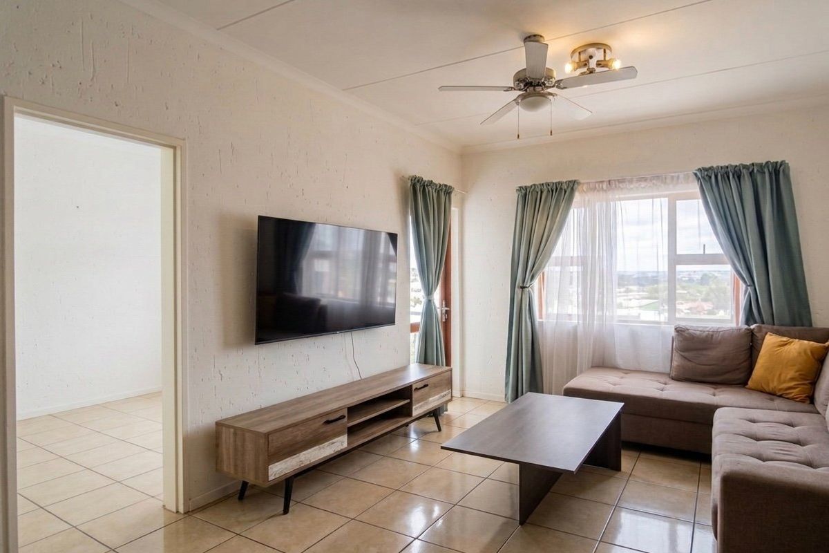 A bright living room featuring tiled flooring, a ceiling fan, and access to an outdoor area through a sliding door.