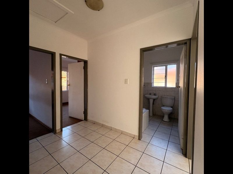 A tiled hallway providing access to a bathroom and adjacent rooms, featuring neutral walls and standard fixtures.