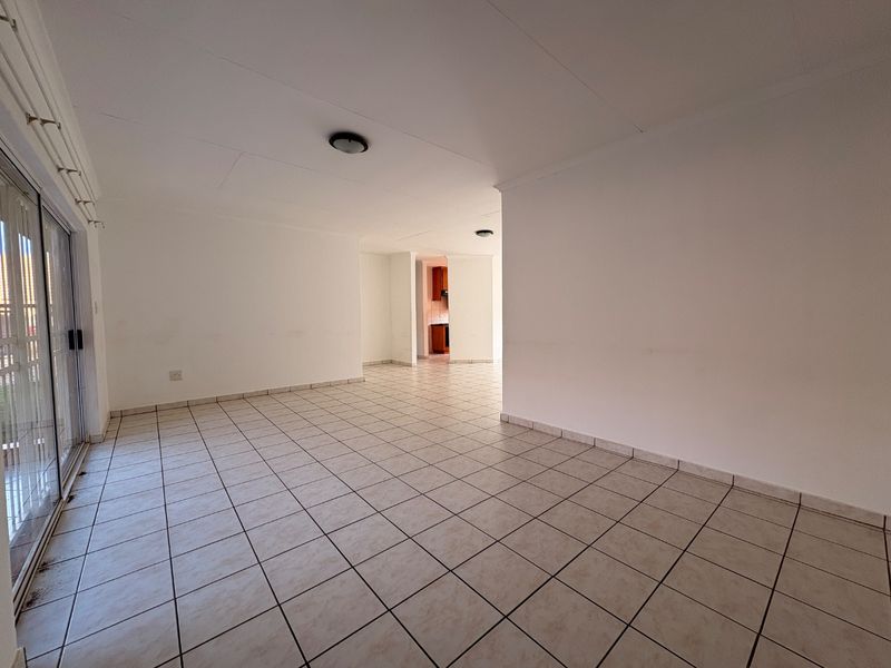 Spacious open-plan living area featuring neutral tiled flooring and a large sliding glass door providing access to the exterior.