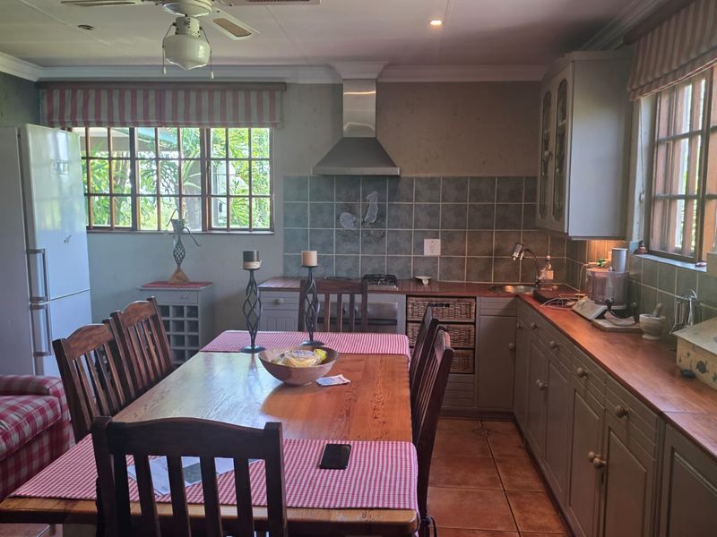 Open-plan kitchen and dining area featuring wooden countertops, tiled backsplash, stainless steel extractor fan, and ample built-in cabinetry with natural light.