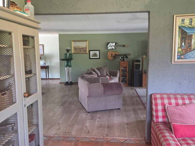 Spacious living area featuring laminate flooring and textured walls, providing an open-plan layout connecting to adjacent living spaces.