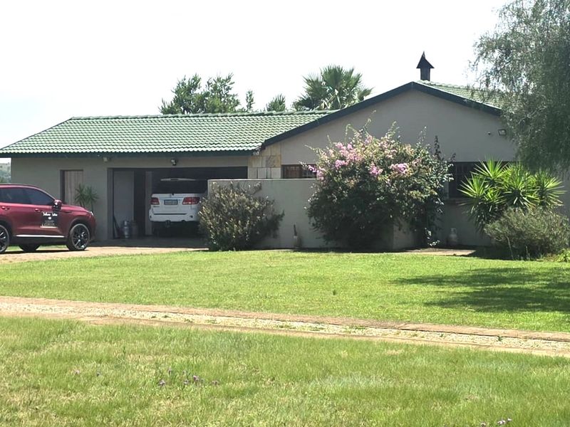 Front view of a farm-style residence featuring a tiled roof, double garage, and surrounding garden space.