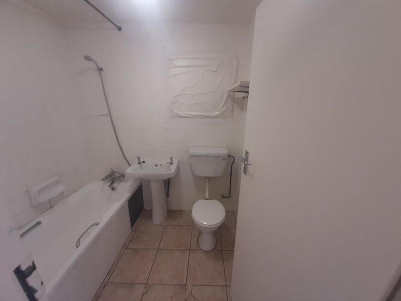 A dated bathroom featuring a standard bathtub, pedestal basin, and toilet, requiring significant renovation and cosmetic updates to improve its condition.