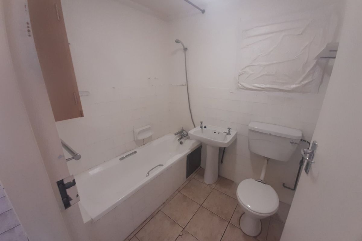 A dated bathroom featuring a standard bathtub, pedestal basin, and toilet, requiring cosmetic updates and renovation to improve its overall condition and appeal.