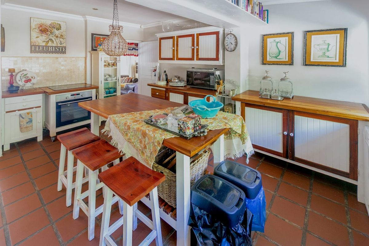 A rustic-style kitchen featuring wooden countertops, built-in cabinetry, a built-in oven, and traditional terracotta tile flooring.