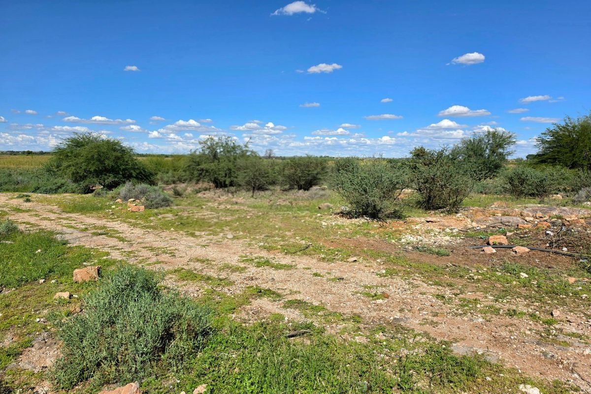 A view of a vacant residential plot featuring natural terrain, native shrubs, and open space, suitable for future development.