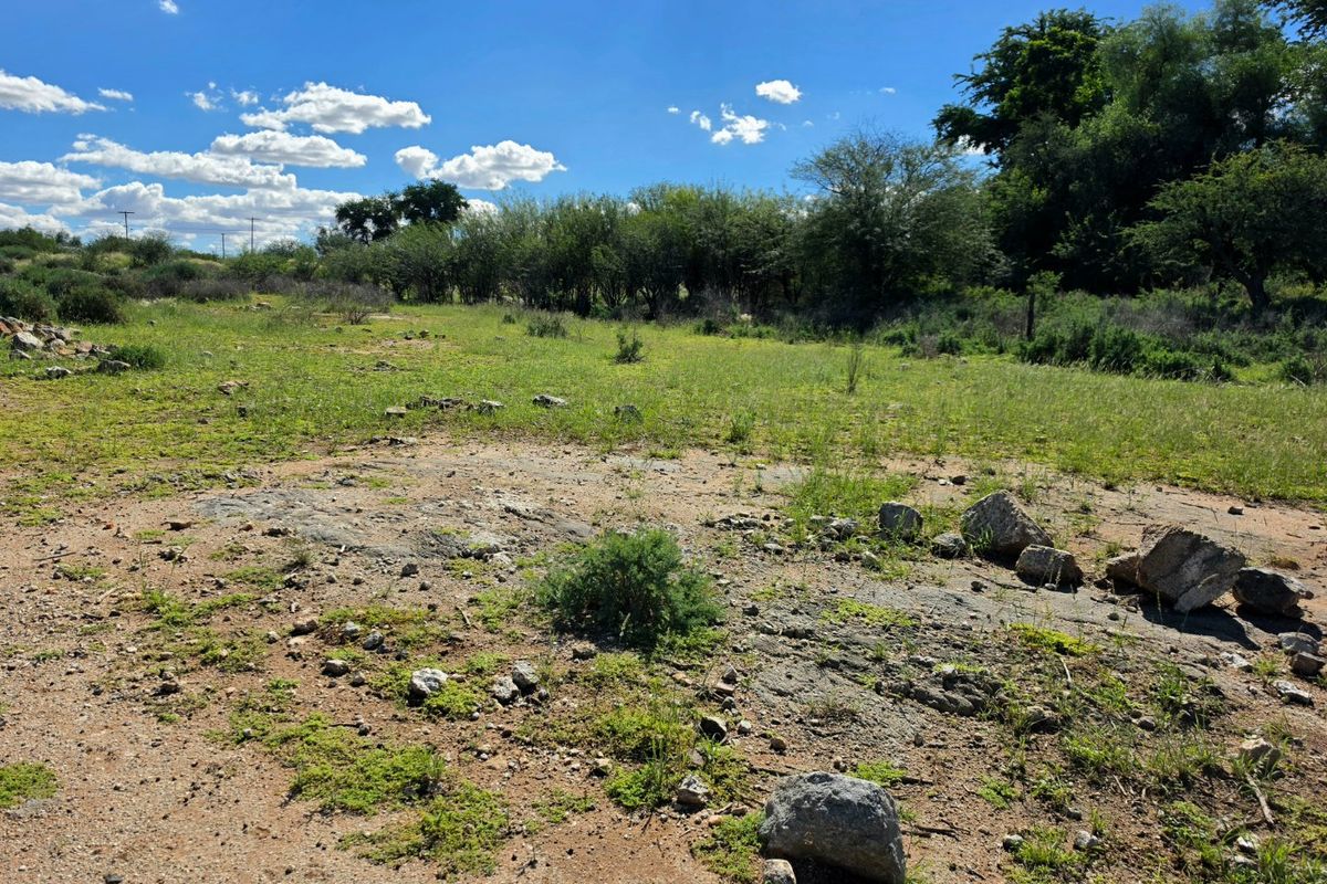 A view of the vacant residential land featuring natural vegetation and rocky terrain under a clear blue sky.