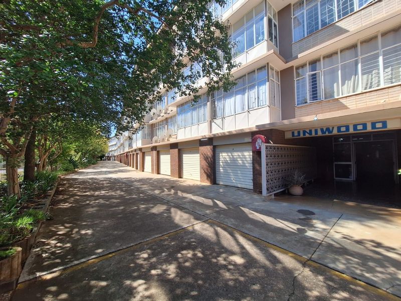 Exterior view of the Uniwood apartment complex featuring a row of garage units and a concrete driveway approach.