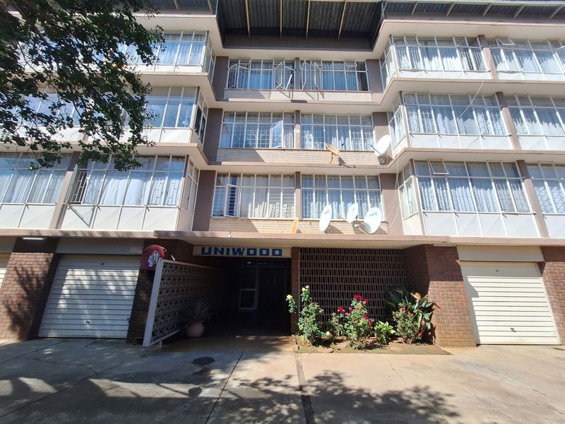 Front elevation of the Uniwood apartment complex featuring brick facade, multiple garage doors, and large windows with metal frames.