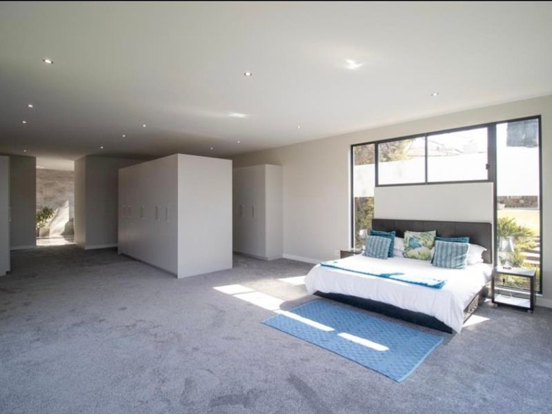 Spacious bedroom featuring extensive built-in cupboards, recessed downlighting, and large windows providing ample natural light.