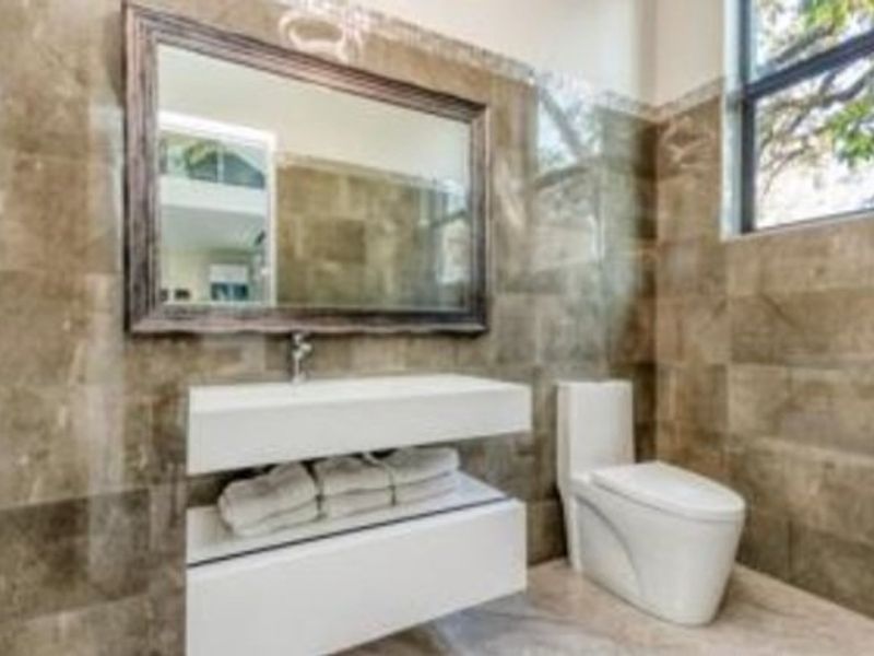 Modern bathroom featuring full-height wall tiling, a sleek wall-mounted vanity with integrated basin, and a contemporary back-to-wall toilet.