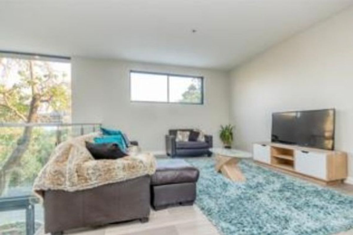 A bright living room featuring large windows, a glass balustrade overlooking the exterior, and neutral wall finishes.