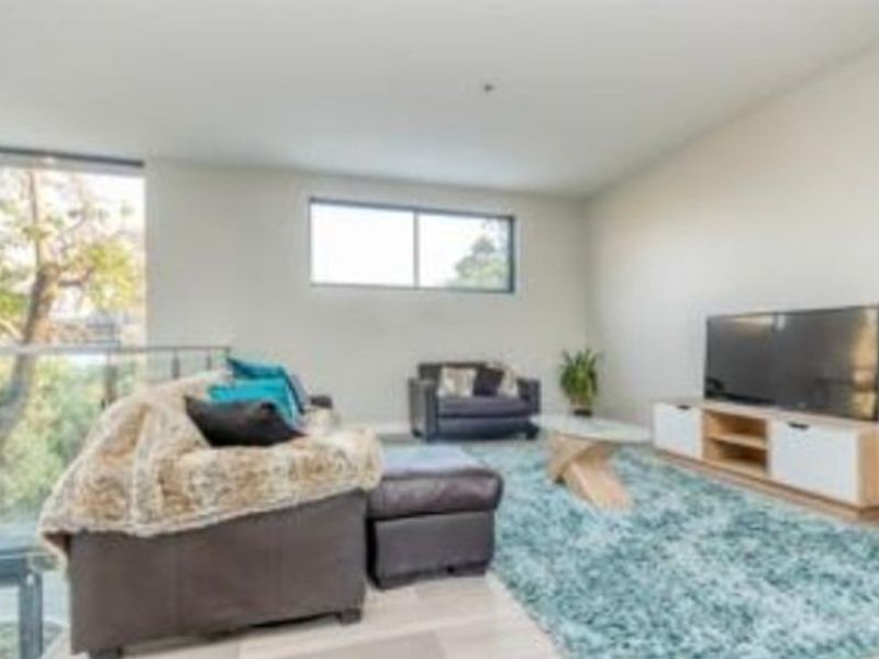 A bright living room featuring large windows, a glass balustrade overlooking the exterior, and neutral wall finishes.