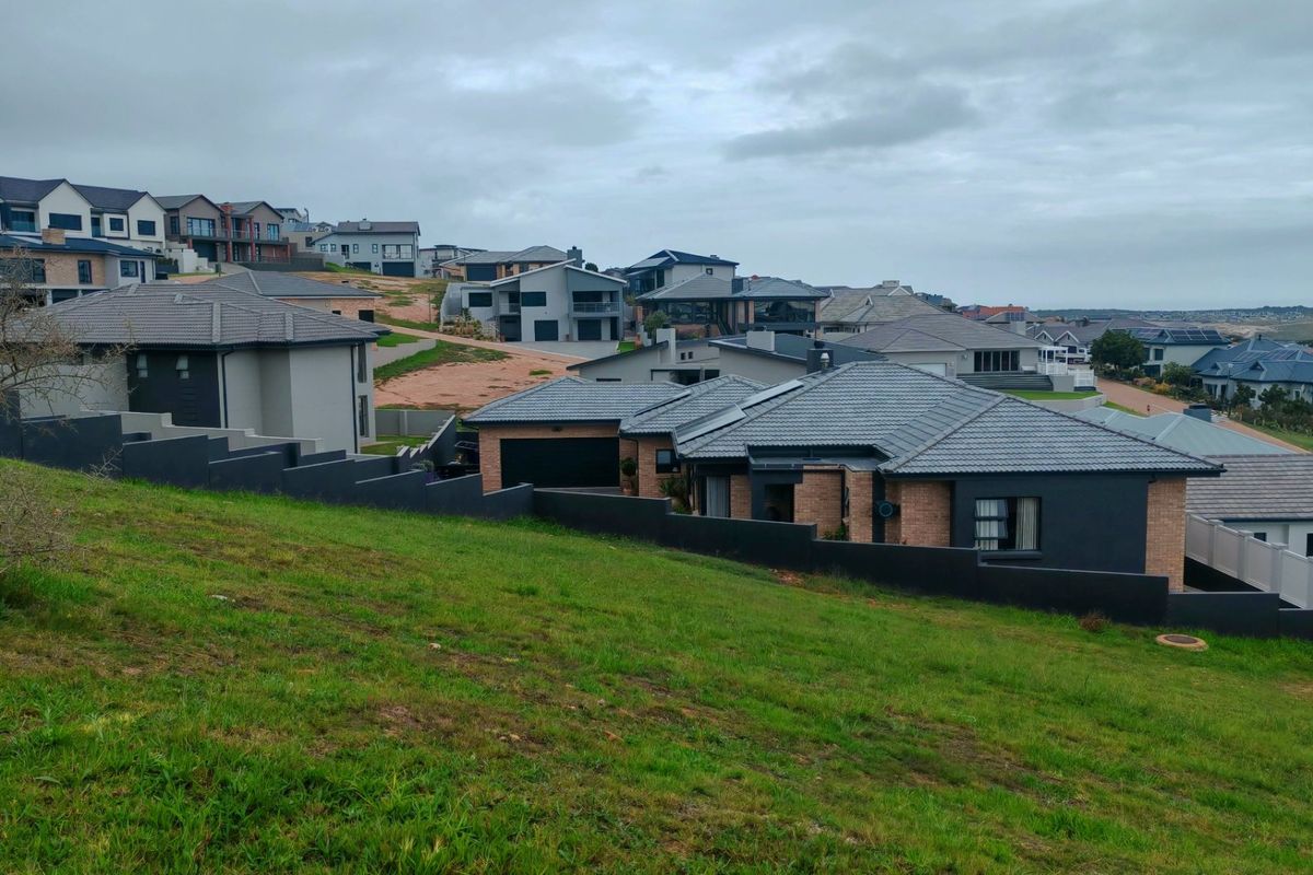 An elevated view of a sloped vacant residential plot situated within an established modern housing estate.