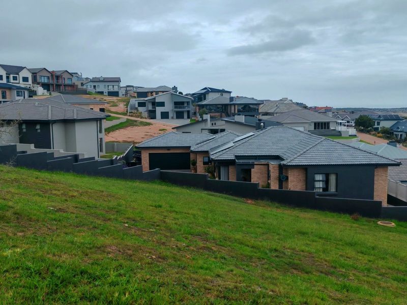 An elevated view of a sloped vacant residential plot situated within an established modern housing estate.